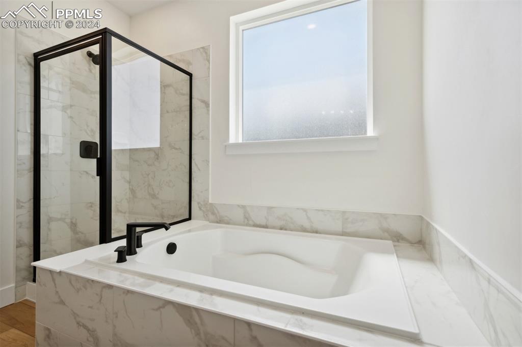 Image 8 of 15: Bathroom featuring hardwood / wood-style flooring and plus walk in shower