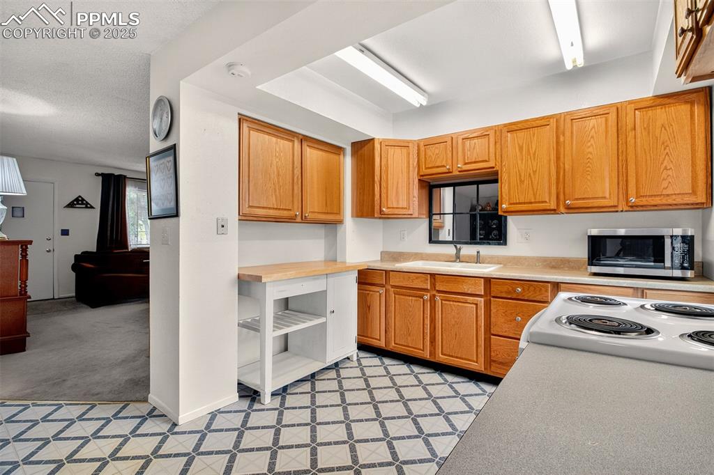 Image 19 of 37: Another view of the kitchen with stove, microwave, 