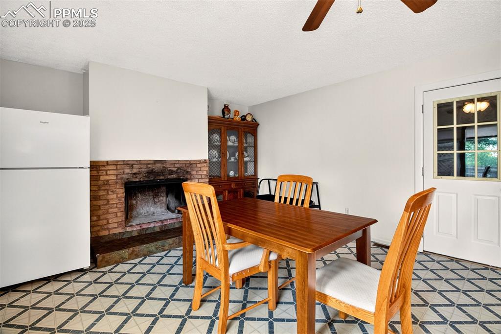 Image 21 of 37: Dining area with a fireplace and ceiling fan