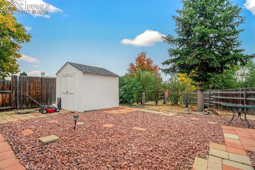Image 28 of 37: Fenced backyard featuring a storage shed and back patio area