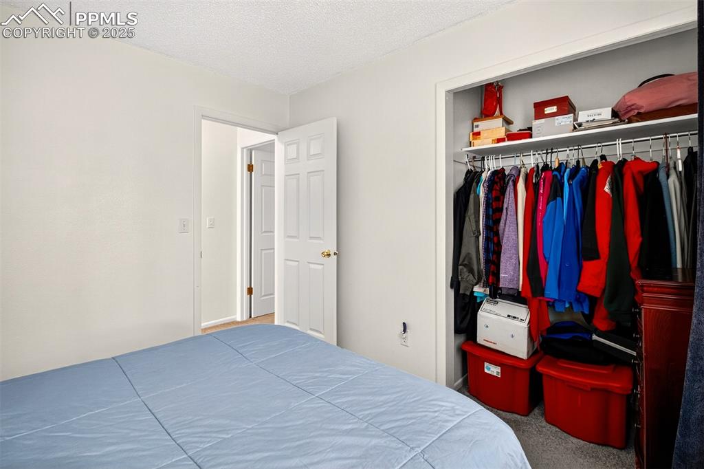 Image 30 of 37: Carpeted bedroom featuring a textured ceiling and a closet