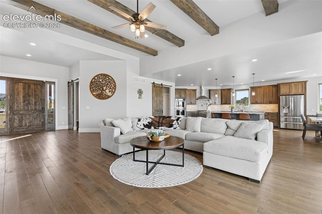 Image 10 of 50: Vaulted ceiling with exposed wood beams, wood-finish flooring, recessed lig