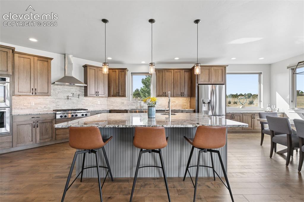Image 13 of 50: Gourmet kitchen featuring a large central island with seating, stainless st