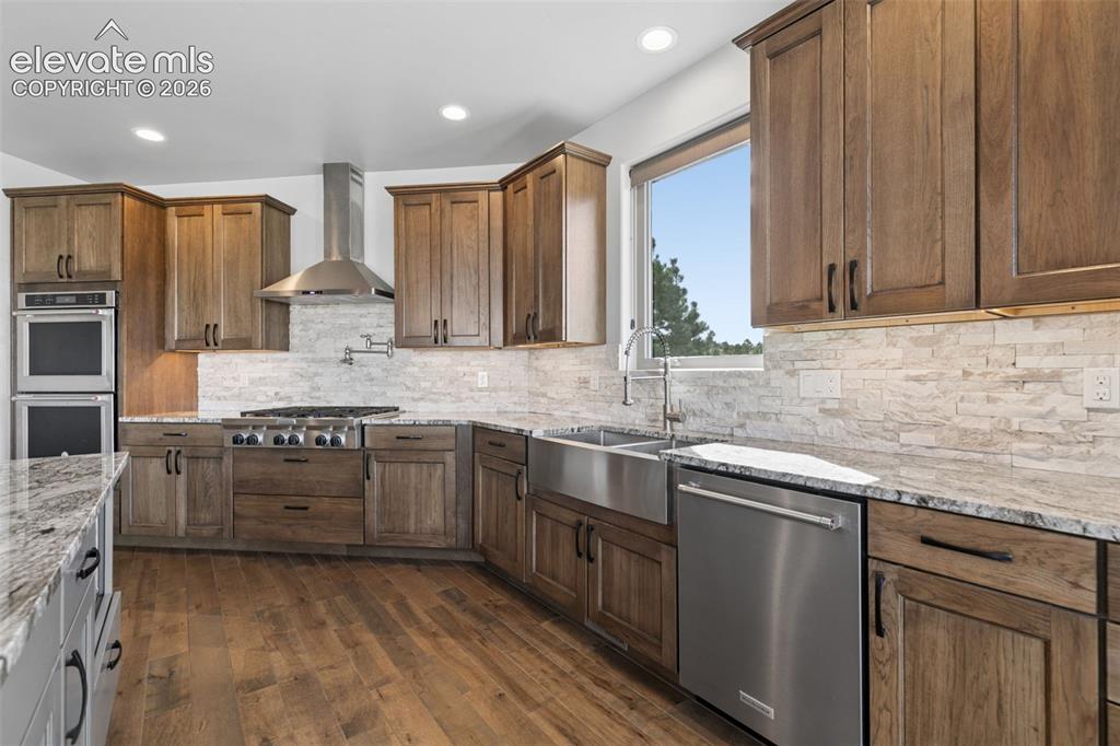 Image 17 of 50: Wood-finish cabinetry complemented by light-toned stacked stone backsplash