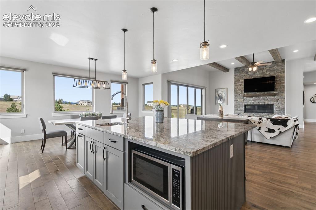 Image 18 of 50: Kitchen island with stone-finish countertop, under-counter microwave, and p