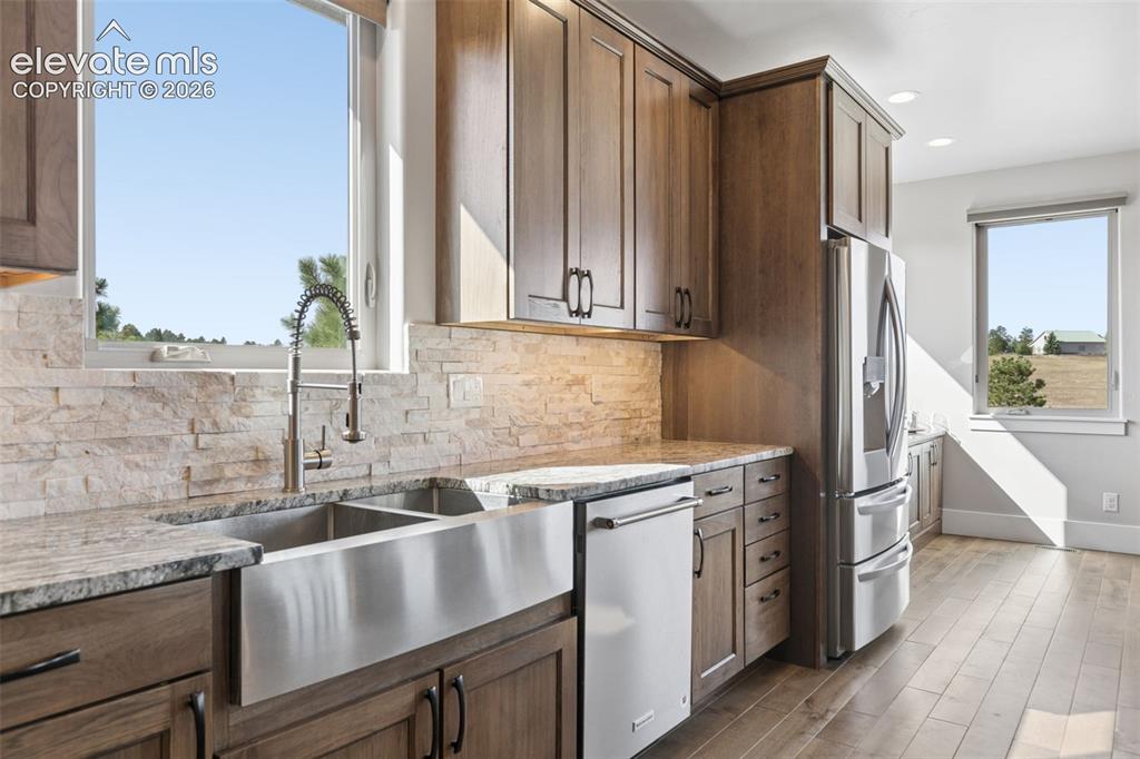 Image 19 of 50: Wood-finish cabinetry, stainless steel farmhouse sink, stacked stone backsp