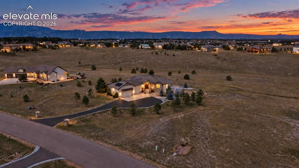 Image 2 of 50: Sweeping landscape with a single-story residence, asphalt driveway, and sur