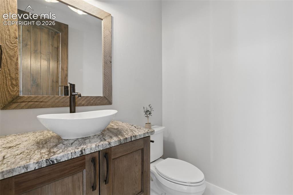 Image 21 of 50: Wood-finish vanity with a vessel sink, stone countertop, and oil-rubbed bro