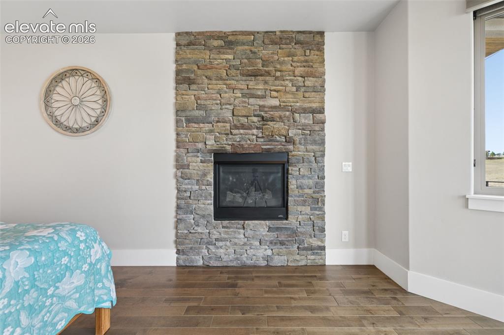 Image 23 of 50: Floor-to-ceiling stone-clad fireplace with a black firebox, wood-finish flo