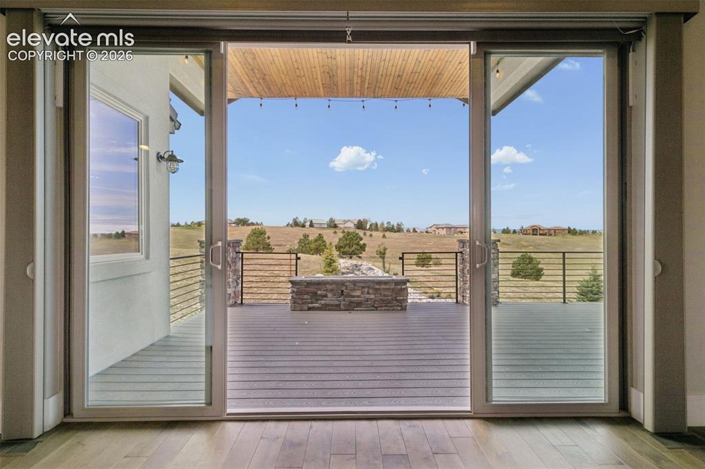 Image 25 of 50: Sliding glass doors opening to an outdoor deck with a stone-clad fire pit, 