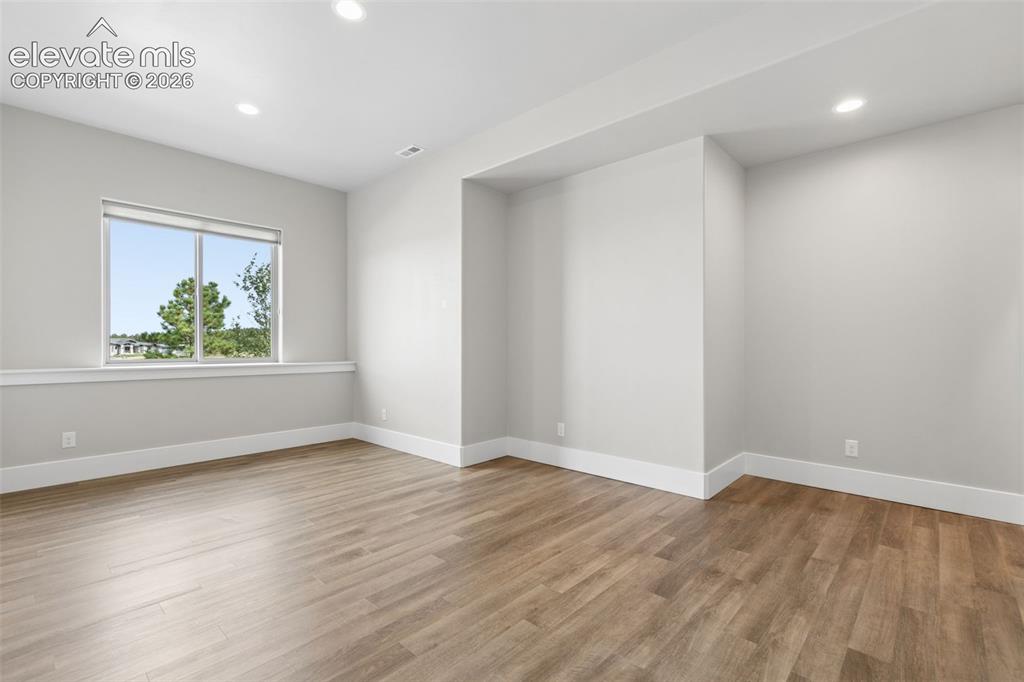 Image 31 of 50: Recessed ceiling lights, wood-finish flooring, white trim, and a window wit