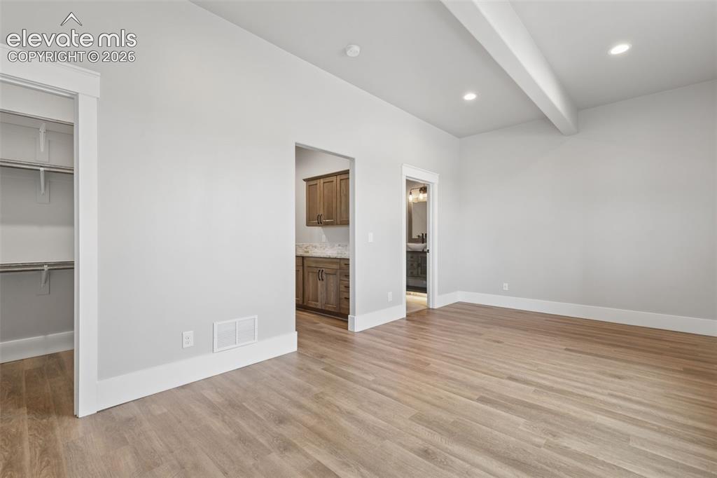 Image 32 of 50: Vaulted ceiling with exposed beam, recessed lighting, wood-finish flooring,