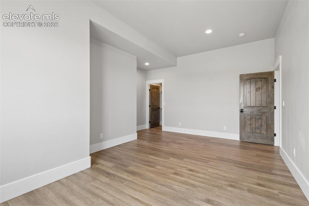 Image 36 of 50: Spacious room featuring wood-finish flooring, light gray walls, white trim,