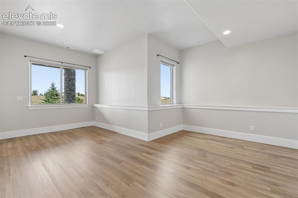 Image 37 of 50: Recessed ceiling lighting, wood-finish flooring, white baseboards, chair ra