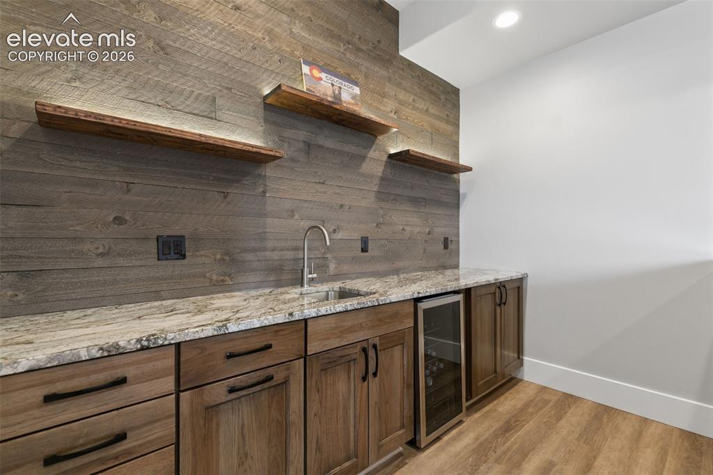 Image 40 of 50: Wood-finish flooring, built-in cabinetry, stone countertop, integrated beve