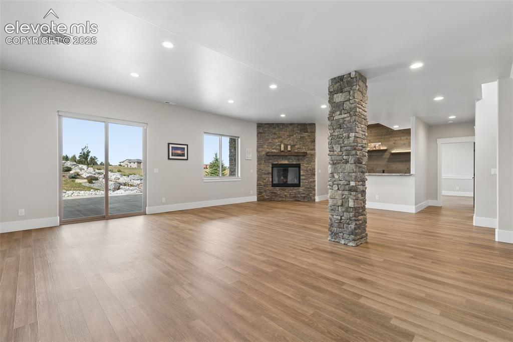 Image 41 of 50: Spacious living area featuring wood-finish flooring, a stone-clad fireplace
