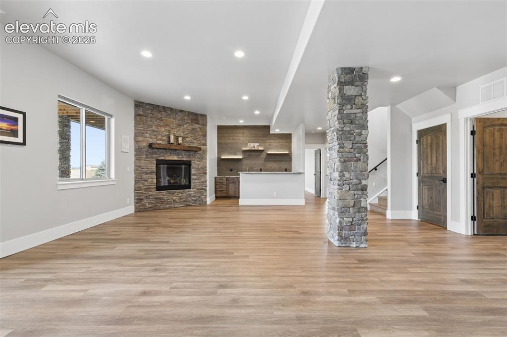 Image 42 of 50: Spacious interior with wood-finish flooring, a stone-accented fireplace wit