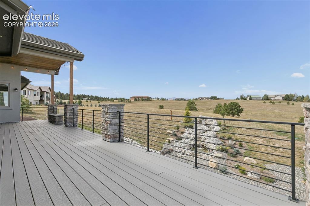 Image 43 of 50: Expansive outdoor deck with composite decking, cable railing, and stone-cla
