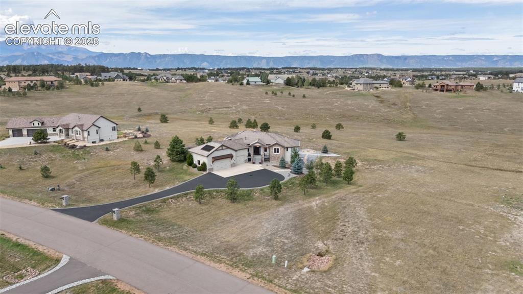 Image 47 of 50: Expansive property featuring a paved driveway, attached garage, and mountai
