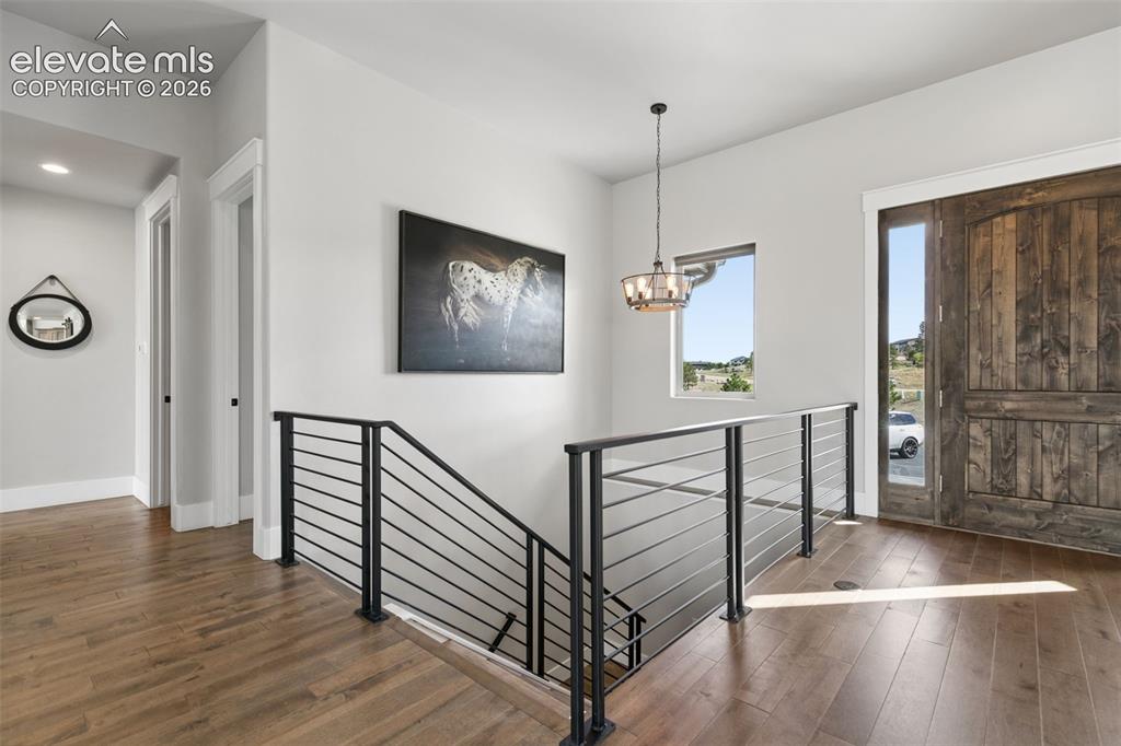 Image 6 of 50: Rich wood-finish flooring, sleek horizontal metal railing, and a rustic woo