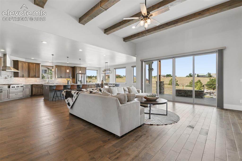 Image 7 of 50: Vaulted ceilings with exposed wood beams, expansive wood-finish flooring, a
