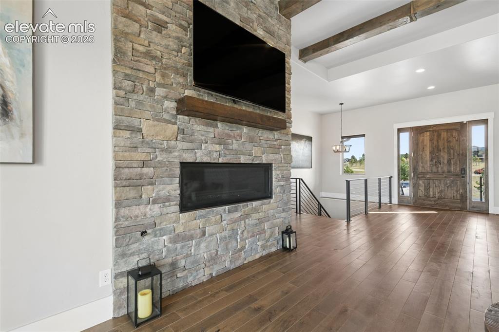 Image 9 of 50: Stone-clad fireplace with wood mantle, wood-finish flooring, exposed ceilin