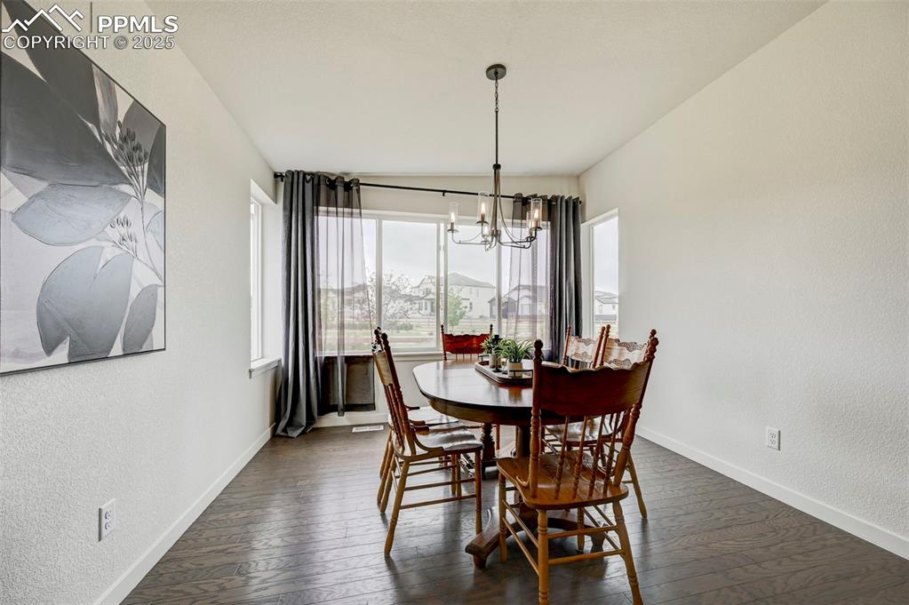 Image 10 of 48: Dining room with a chandelier, baseboards, dark wood-type flooring, and a t