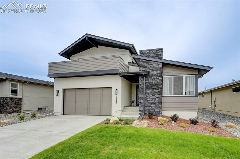 Image 2 of 48: Modern home featuring driveway, a front yard, stucco siding, and an attache