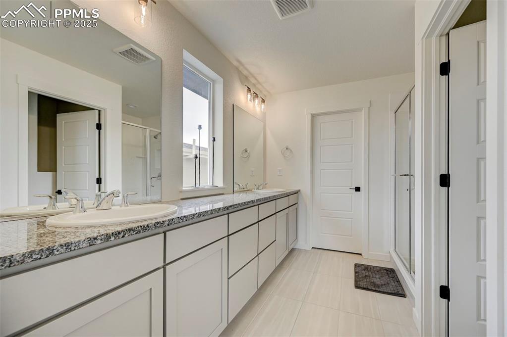 Image 20 of 48: Full bath featuring a shower stall, double vanity, and tile patterned floor