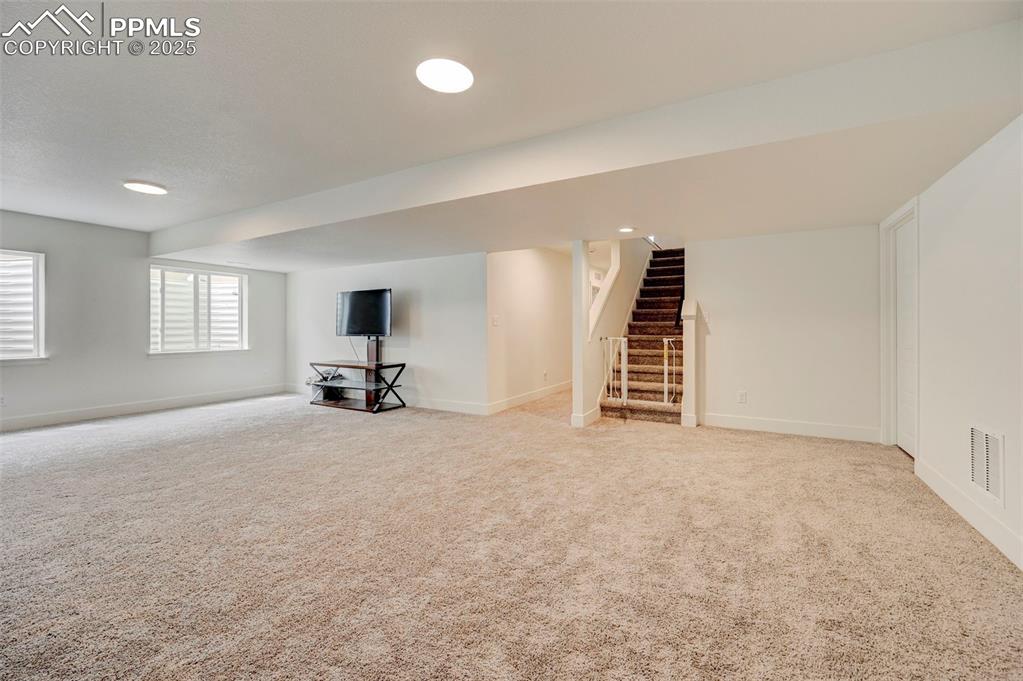 Image 36 of 48: Basement featuring carpet, stairs, and baseboards