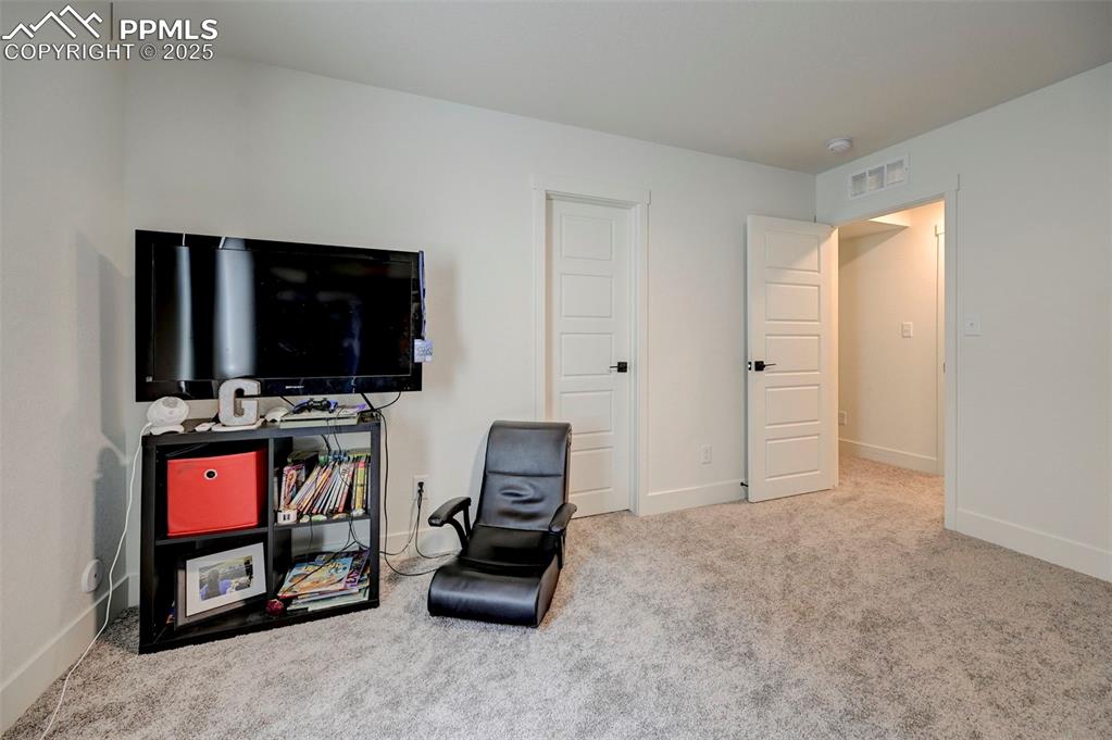 Image 38 of 48: Living area with carpet flooring and baseboards