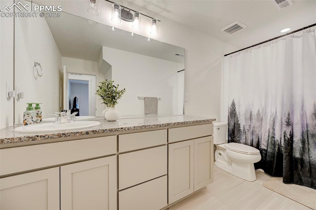 Image 40 of 48: Bathroom with toilet, vanity, and tile patterned flooring