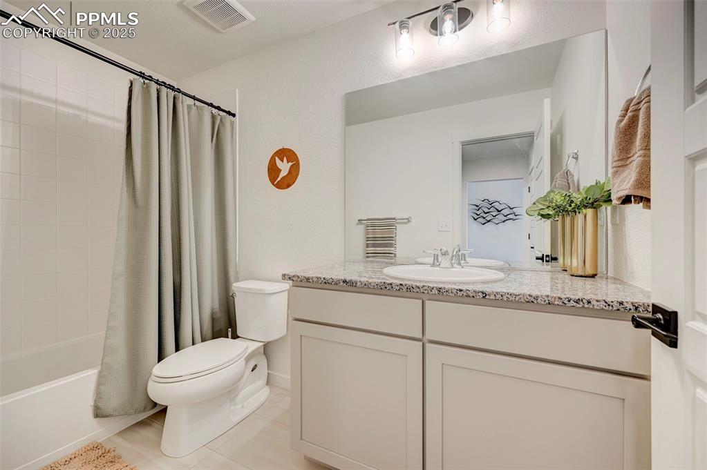 Image 41 of 48: Bathroom with toilet, vanity, tile patterned floors, and shower / tub combo