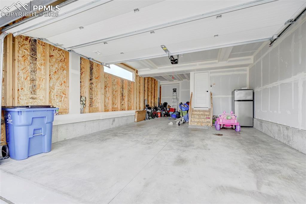 Image 44 of 48: Garage with freestanding refrigerator and a garage door opener