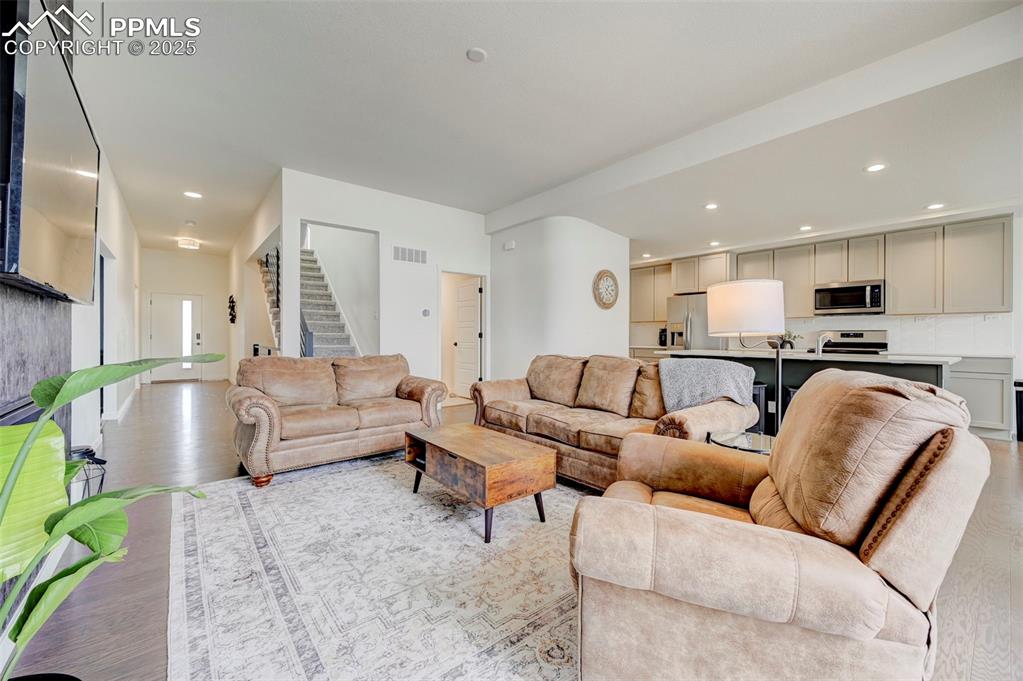 Image 7 of 48: Living area with stairs, light wood-style flooring, and recessed lighting
