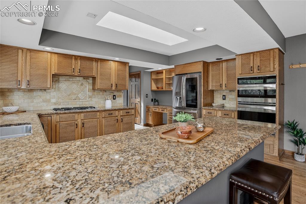 Image 15 of 42: Kitchen featuring tasteful backsplash, a skylight, appliances with stainles