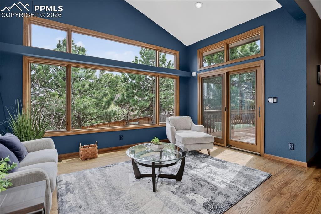 Image 7 of 42: Living area with wood finished floors and vaulted ceiling