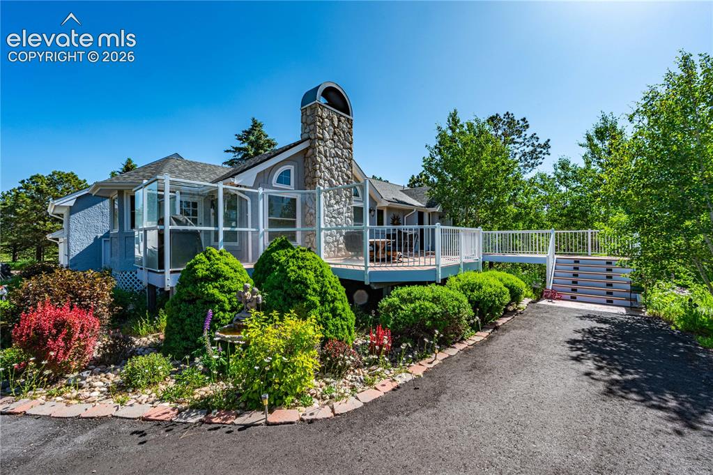 Image 37 of 50: Beautifully landscaped front elevation with mature trees and inviting curb