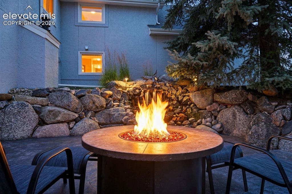Image 44 of 50: Outdoor patio featuring a circular fire pit with decorative glass media, a