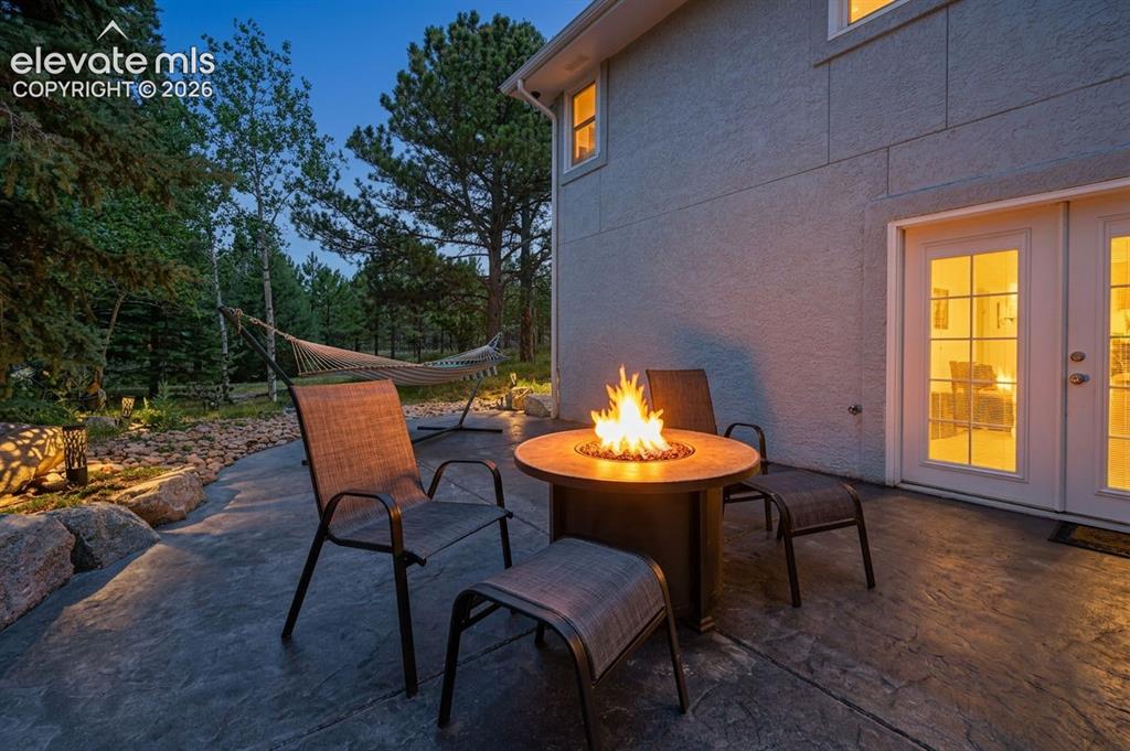 Image 45 of 50: Stucco exterior featuring a stamped concrete patio, built-in fire pit, and