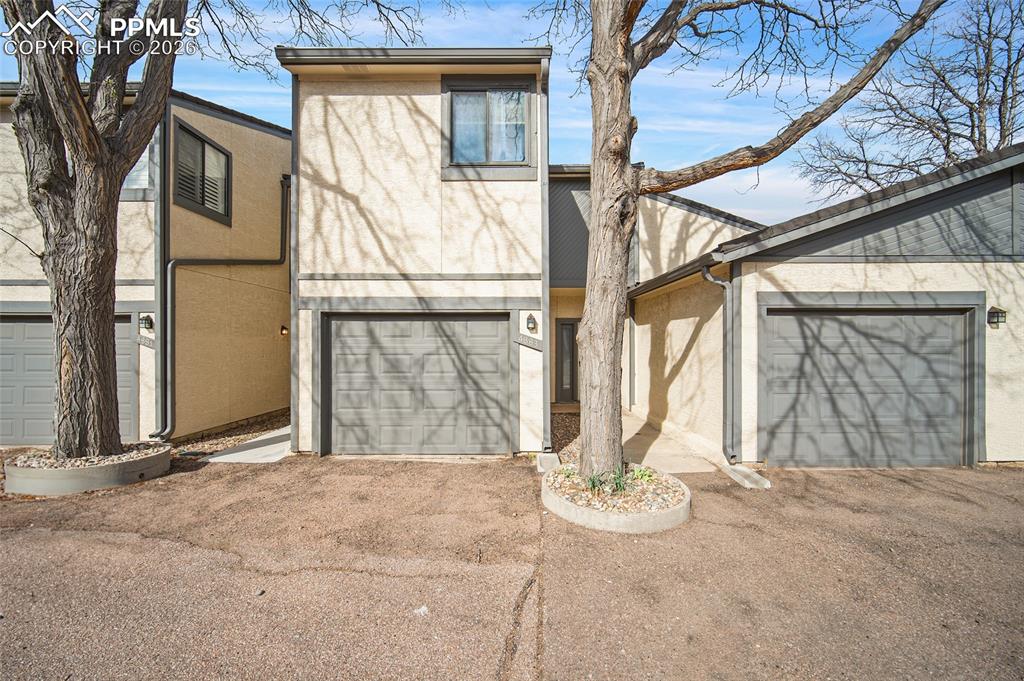Image 1 of 31: Mid-century home featuring stucco siding, an attached garage, and asphalt d