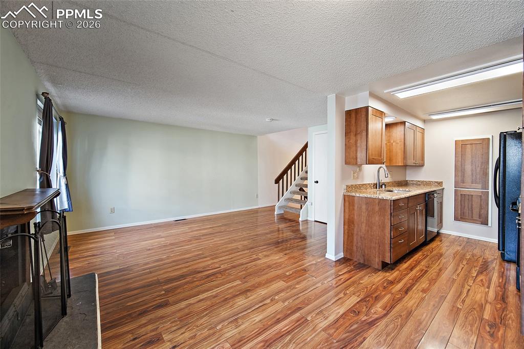 Image 10 of 31: Kitchen featuring a textured ceiling, light stone counters, open floor plan