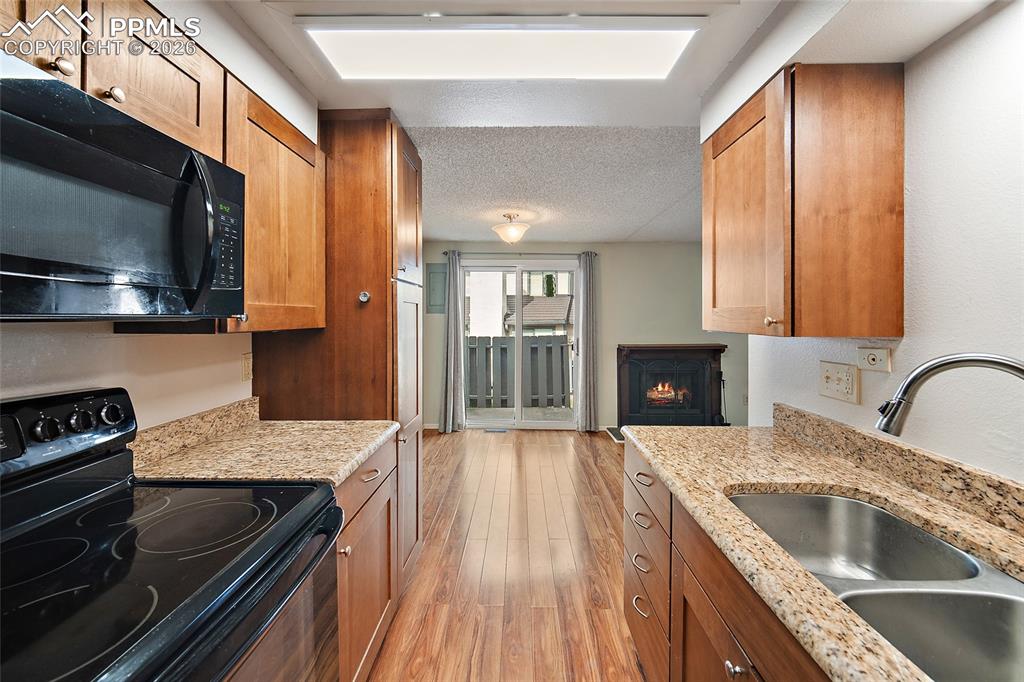 Image 14 of 31: Kitchen featuring black appliances, light stone counters, light wood-style 