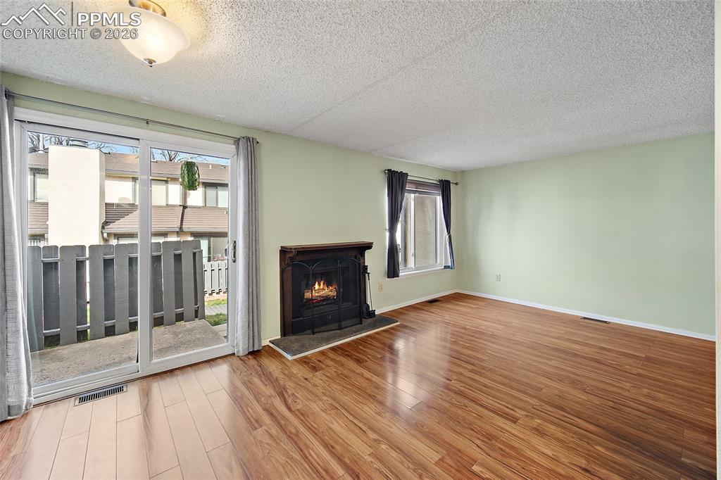 Image 15 of 31: Unfurnished living room featuring a textured ceiling, light wood-style floo