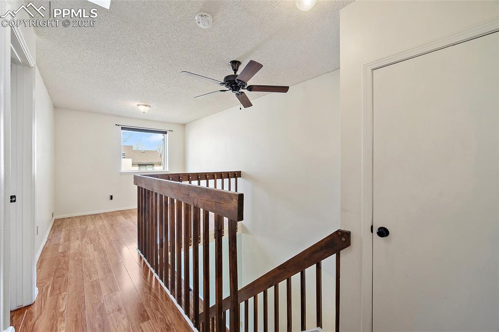 Image 22 of 31: Corridor featuring an upstairs landing, light wood-type flooring, and a tex