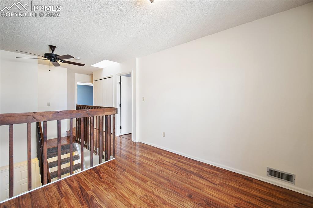 Image 23 of 31: Unfurnished room with wood finished floors, a textured ceiling, and ceiling