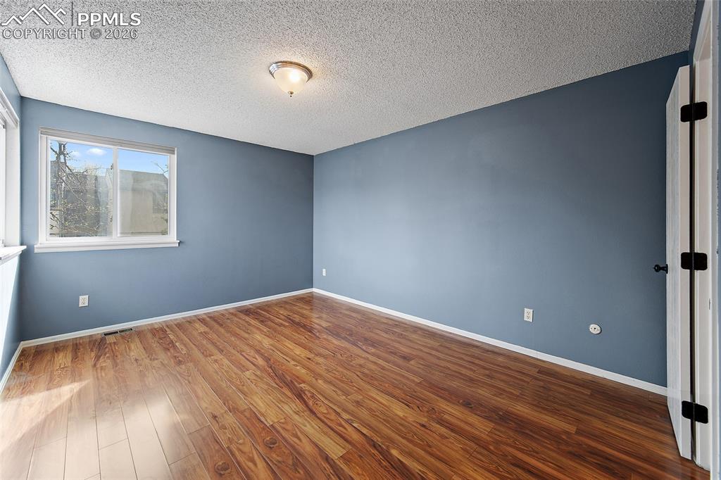 Image 27 of 31: Spare room featuring dark wood-style flooring and a textured ceiling