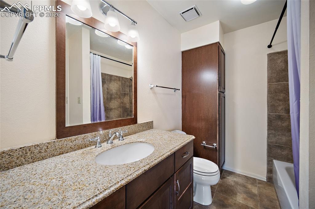 Image 29 of 31: Bathroom with vanity, shower / bathtub combination with curtain, and dark t