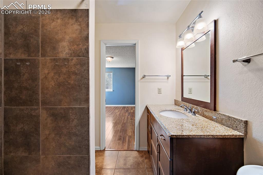 Image 31 of 31: Bathroom with vanity, tile patterned floors, a textured ceiling, and a text