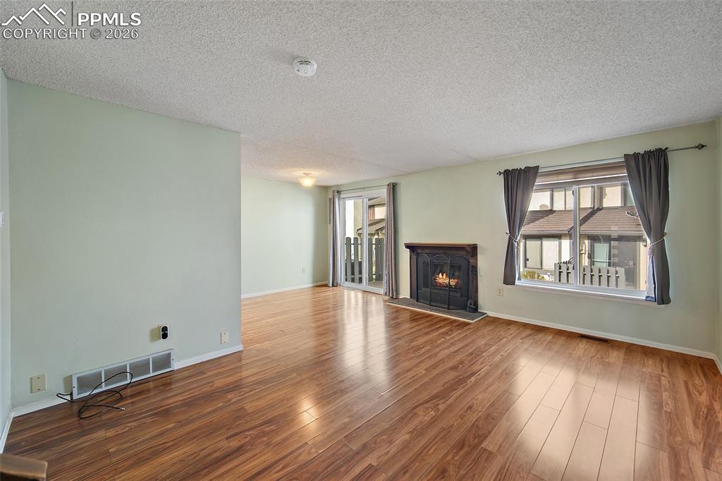 Image 8 of 31: Unfurnished living room featuring dark wood-type flooring, a textured ceili